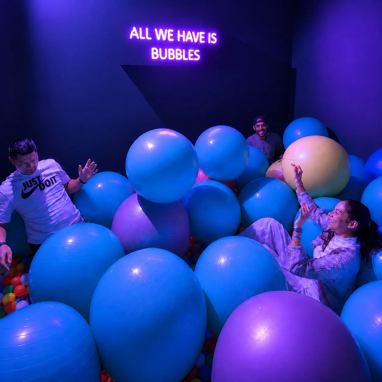 A birthday group laughing and playing among giant balloons in the "All We Have Is Bubbles" room