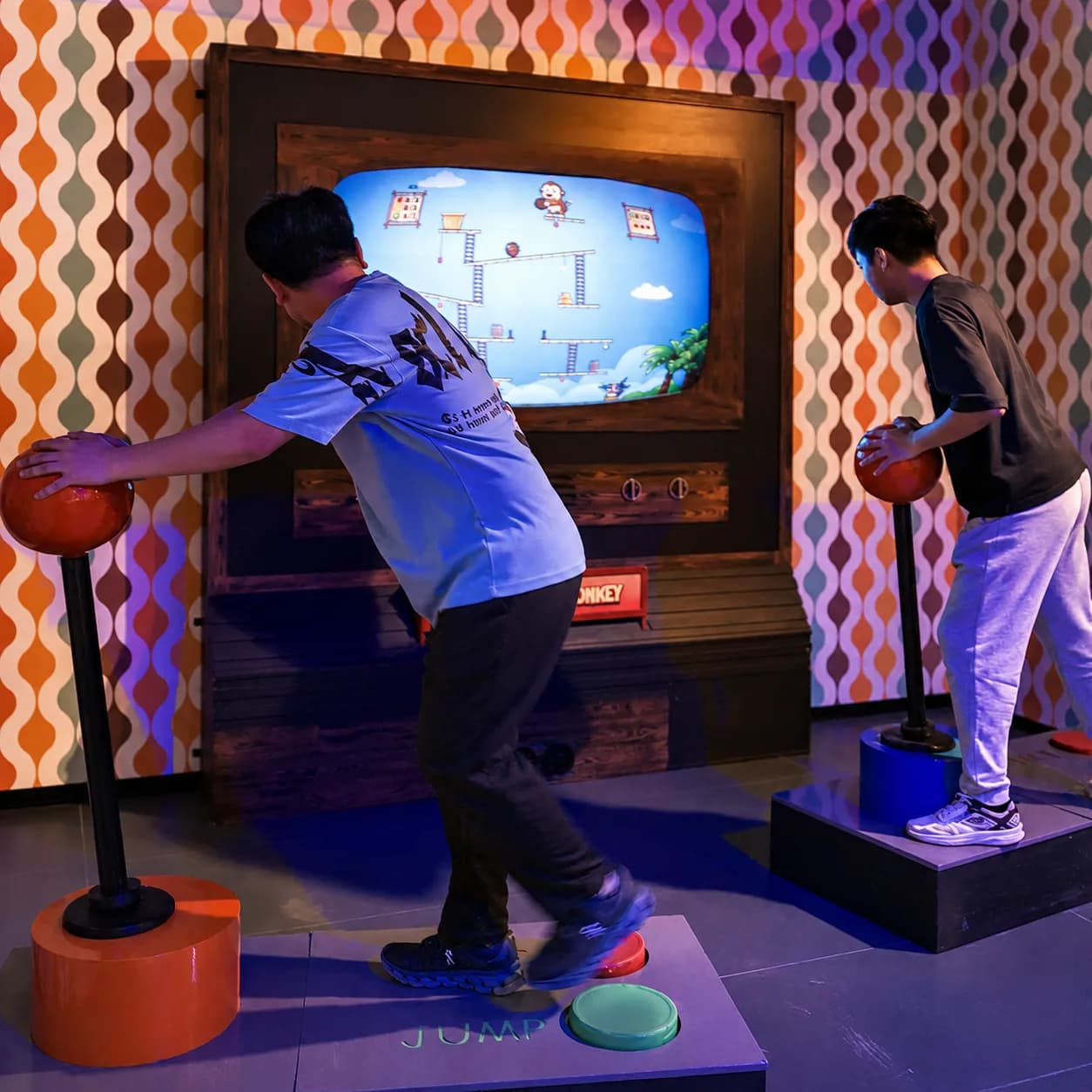 Two students working a retro arcade jump challenge together during a school trip visit