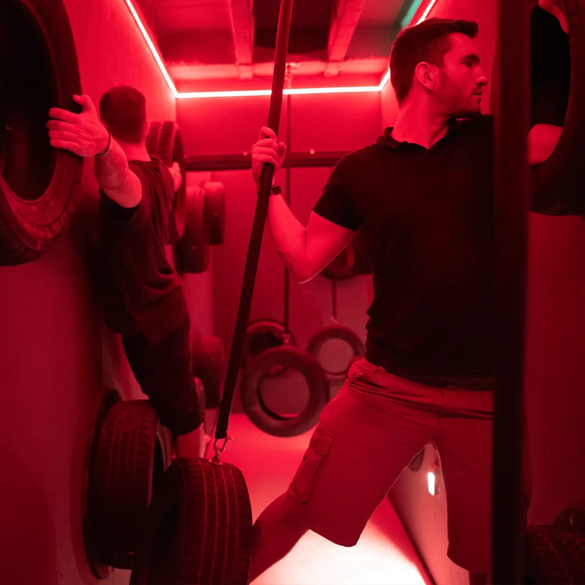 A group climbing a red-lit tire wall together during a social celebration visit