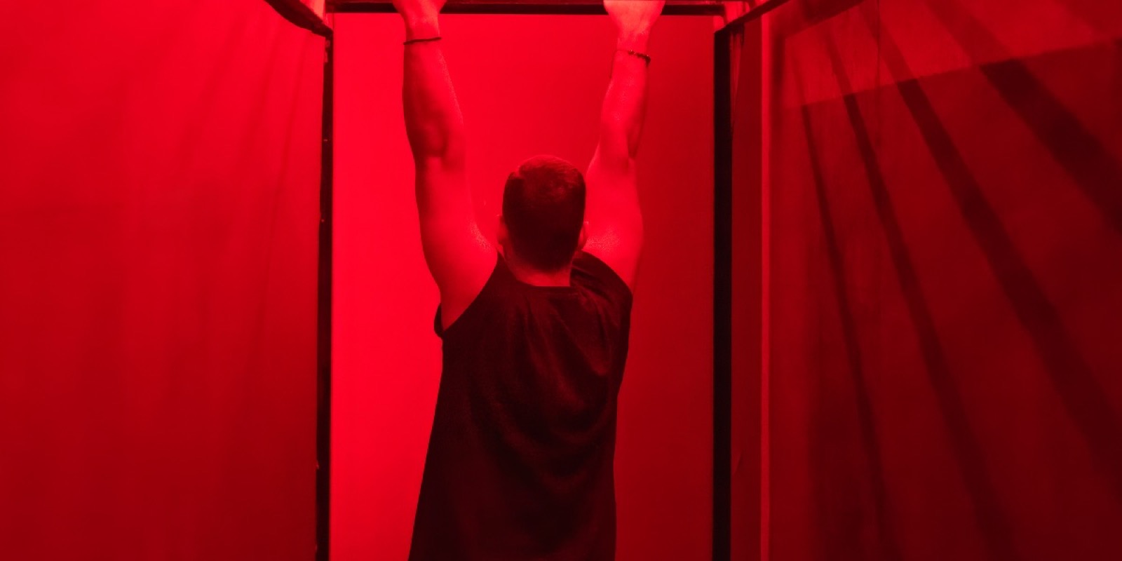 A player hanging from the bar in the red-lit Cardio room