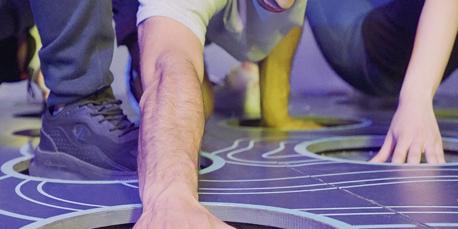 Hands and feet on the lit coloured floor of the Color Twist room